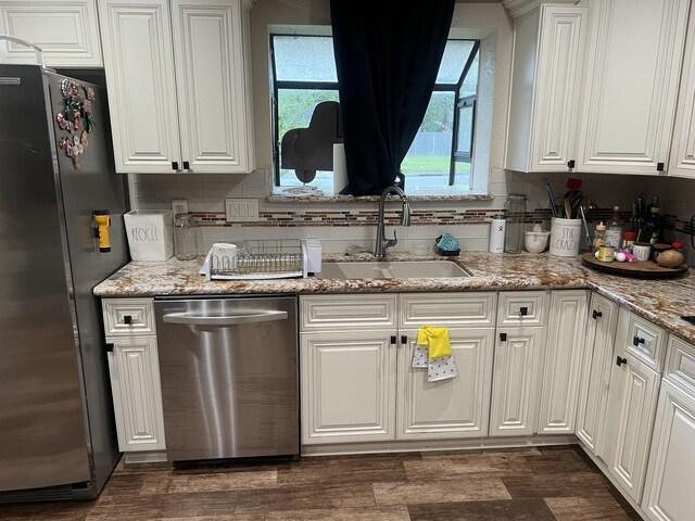 kitchen with sink, appliances with stainless steel finishes, dark wood-type flooring, tasteful backsplash, and white cabinets