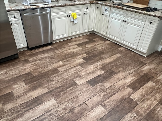 kitchen featuring dark hardwood / wood-style flooring, white cabinets, stainless steel dishwasher, and dark stone counters