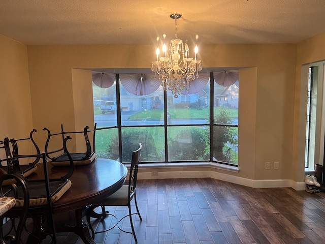 dining space with a textured ceiling, hardwood / wood-style floors, and an inviting chandelier