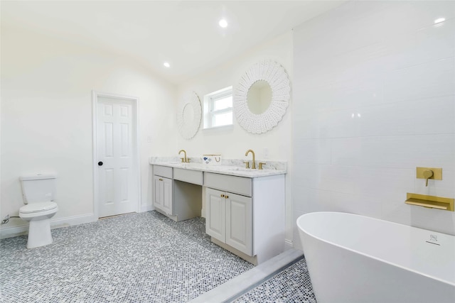 bathroom with a washtub, toilet, vanity, and vaulted ceiling