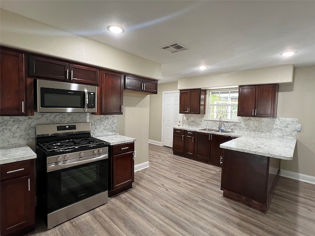 kitchen featuring sink, decorative backsplash, light hardwood / wood-style flooring, and appliances with stainless steel finishes