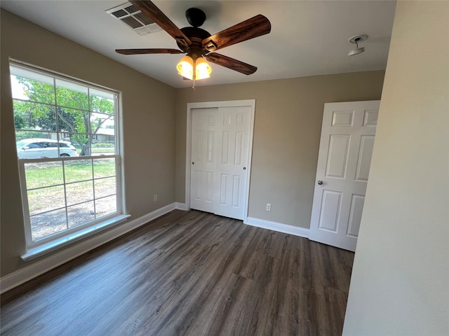 unfurnished bedroom featuring ceiling fan, wood-type flooring, a closet, and multiple windows