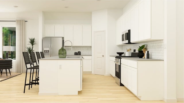 kitchen featuring white cabinetry, stainless steel appliances, an island with sink, and light hardwood / wood-style flooring