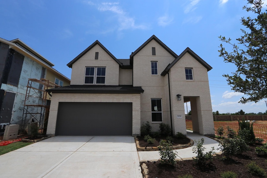 view of front of property featuring a garage, driveway, brick siding, and fence