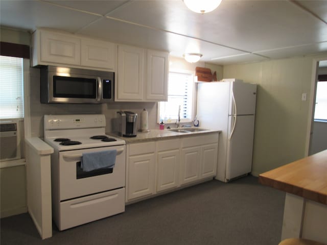 kitchen with sink, wood counters, white appliances, dark carpet, and white cabinetry