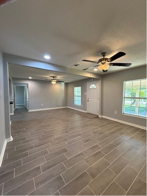 unfurnished room with ceiling fan and a wealth of natural light