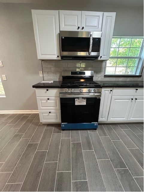 kitchen featuring backsplash, range with gas cooktop, white cabinets, and dark hardwood / wood-style flooring