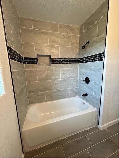 bathroom featuring tile patterned floors, a textured ceiling, and tiled shower / bath combo