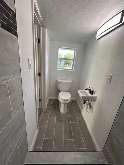 bathroom with tile patterned flooring, toilet, a textured ceiling, and sink