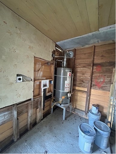 interior space featuring strapped water heater, wooden walls, and wooden ceiling