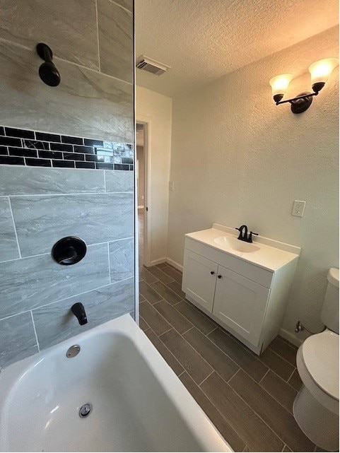 bathroom featuring a textured ceiling, vanity, and toilet