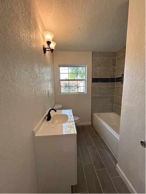 bathroom featuring tile patterned flooring, toilet, a textured ceiling, and vanity