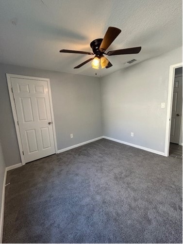 unfurnished bedroom with ceiling fan and dark carpet