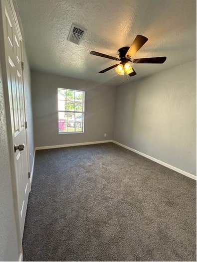 carpeted spare room with ceiling fan and a textured ceiling