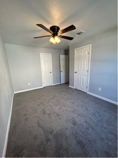 unfurnished bedroom with carpet, a textured ceiling, and ceiling fan