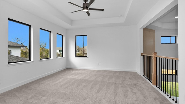 unfurnished room featuring light carpet, a raised ceiling, and ceiling fan