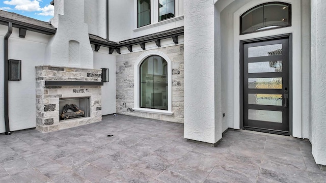 view of exterior entry featuring an outdoor stone fireplace and a patio