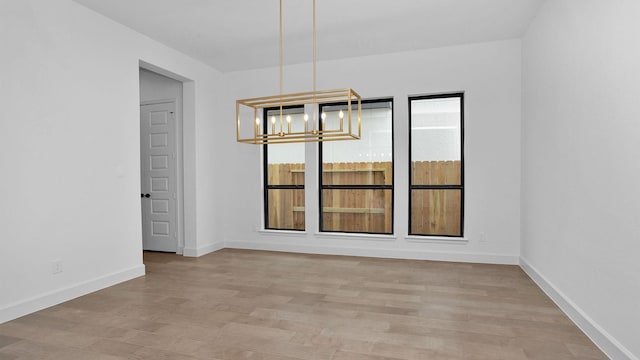 unfurnished dining area with light wood-type flooring and a notable chandelier