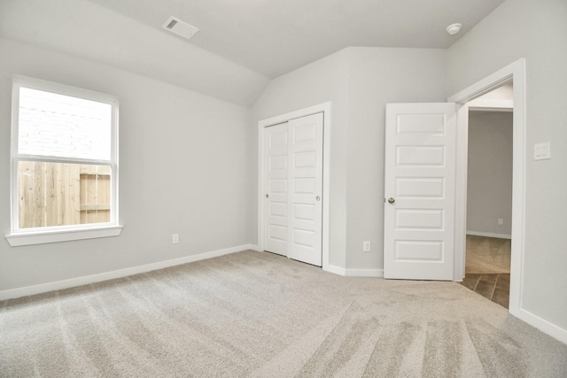 unfurnished bedroom with carpet floors, a closet, baseboards, visible vents, and lofted ceiling