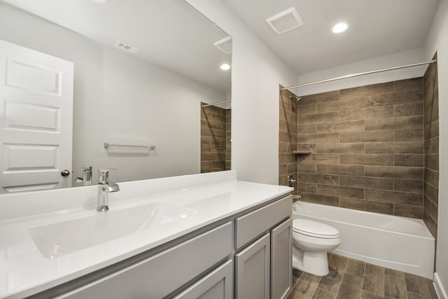 full bathroom with wood-type flooring, tiled shower / bath, vanity, and toilet