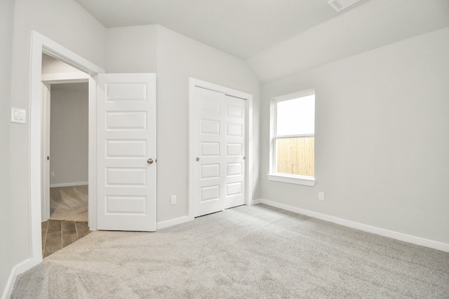 unfurnished bedroom featuring lofted ceiling, light carpet, and a closet