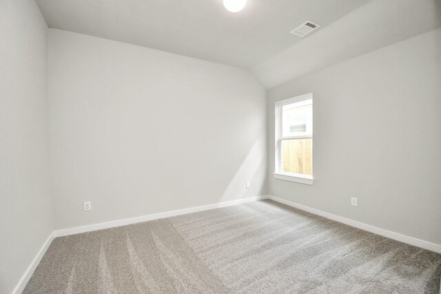 carpeted spare room featuring lofted ceiling, visible vents, and baseboards