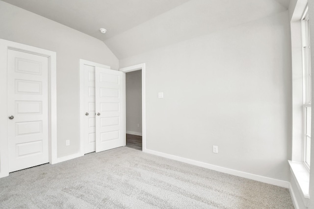 unfurnished bedroom featuring lofted ceiling, carpet flooring, and baseboards