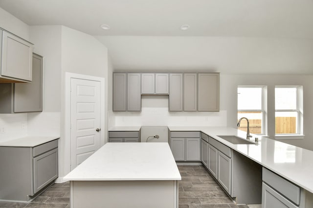 kitchen with sink, tasteful backsplash, dark wood-type flooring, gray cabinets, and a center island