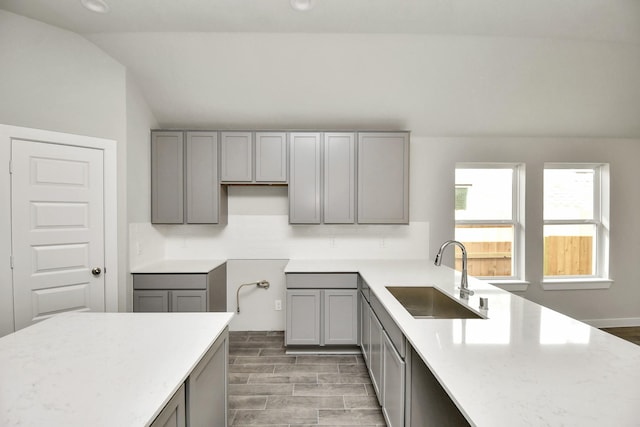 kitchen with lofted ceiling, a sink, and gray cabinets
