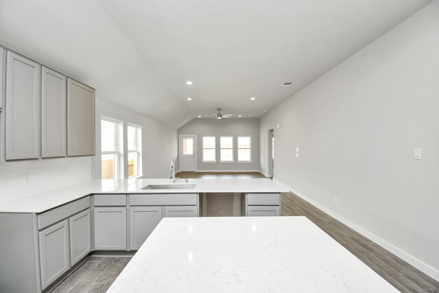 kitchen featuring lofted ceiling, sink, gray cabinets, and dark hardwood / wood-style flooring