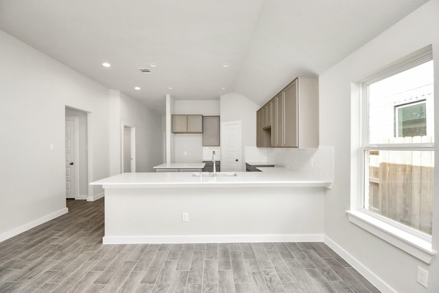 kitchen with light countertops, a sink, a peninsula, and light wood-type flooring