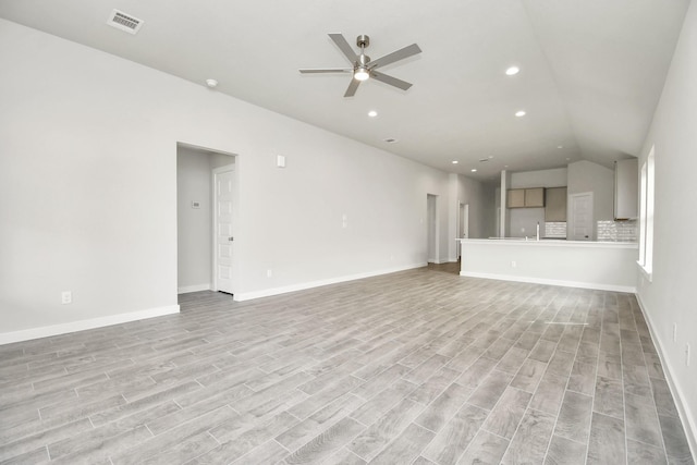 unfurnished living room featuring light wood-type flooring, visible vents, a ceiling fan, and vaulted ceiling