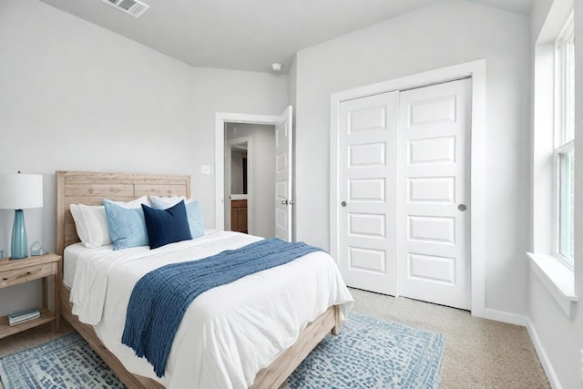 bedroom with baseboards, visible vents, light carpet, and a closet