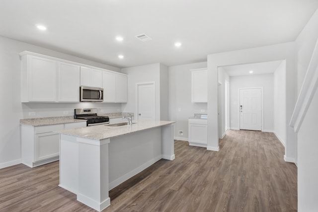 kitchen with a kitchen island with sink, white cabinets, sink, light hardwood / wood-style flooring, and stainless steel appliances