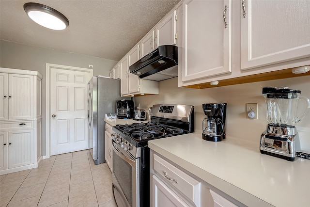 kitchen with white cabinetry, light tile patterned floors, stainless steel gas range oven, and a textured ceiling