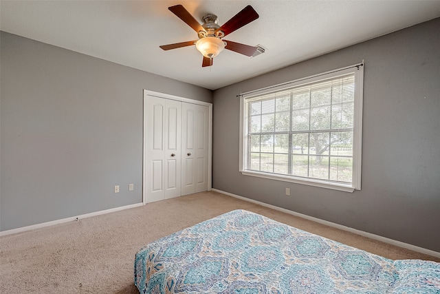 carpeted bedroom featuring a closet, ceiling fan, and multiple windows