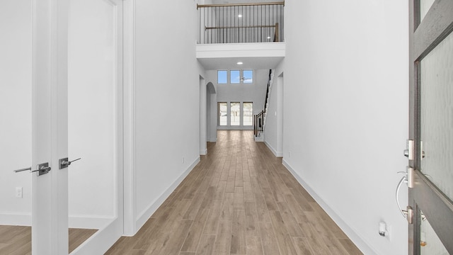 hallway featuring a towering ceiling and light hardwood / wood-style flooring