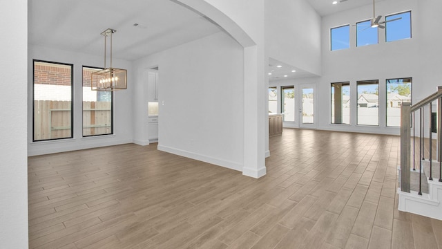 foyer with a towering ceiling, an inviting chandelier, and light wood-type flooring