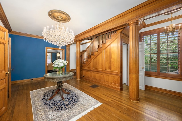 interior space with ornate columns, a notable chandelier, dark wood-type flooring, and ornamental molding