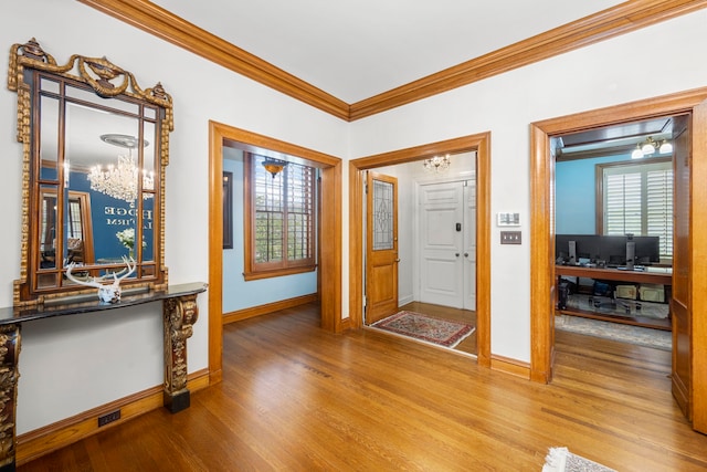 foyer featuring crown molding, wood-type flooring, and a chandelier