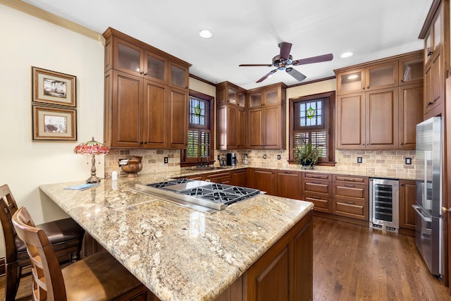 kitchen with ceiling fan, dark hardwood / wood-style floors, tasteful backsplash, beverage cooler, and crown molding