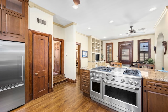 kitchen with ceiling fan, premium appliances, hardwood / wood-style floors, and ornamental molding