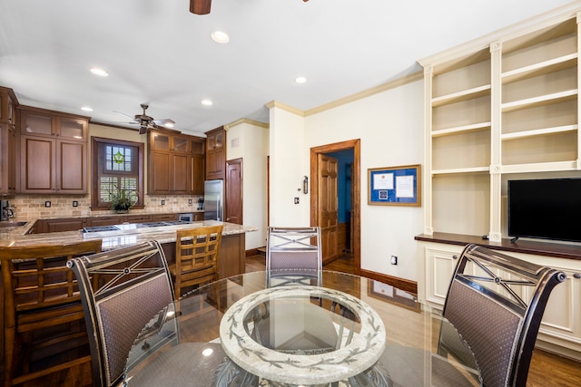 kitchen featuring decorative backsplash, hardwood / wood-style floors, stainless steel refrigerator, crown molding, and ceiling fan