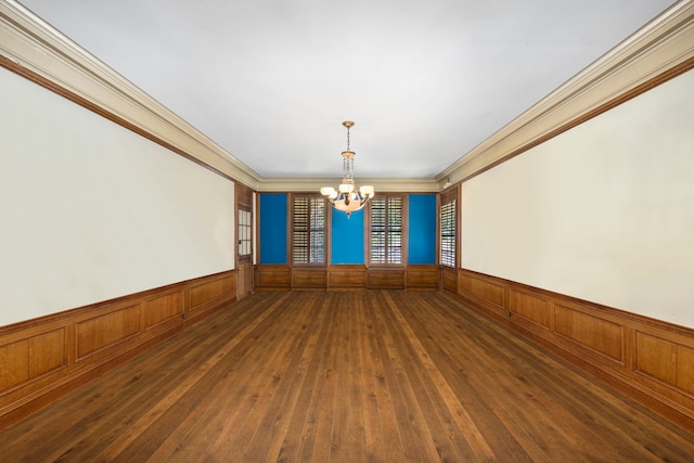 empty room with dark hardwood / wood-style flooring, a notable chandelier, wood walls, and ornamental molding