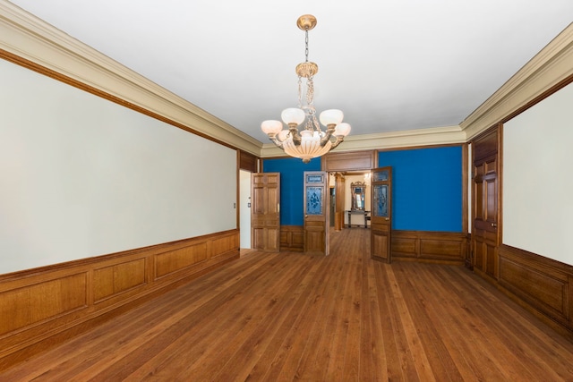 empty room featuring hardwood / wood-style flooring, an inviting chandelier, and crown molding