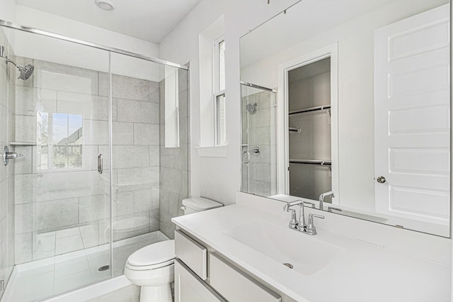 bathroom with a shower with door, toilet, and vanity