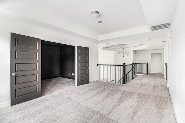 carpeted empty room featuring a chandelier