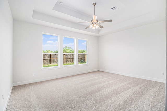 empty room with carpet flooring, ceiling fan, and a raised ceiling