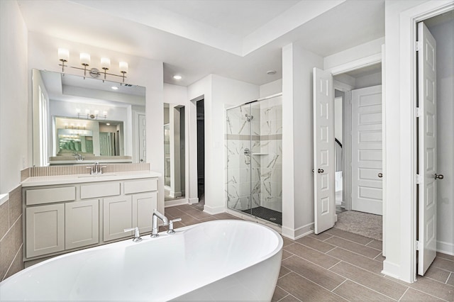 bathroom featuring a tray ceiling, separate shower and tub, vanity, and tile patterned floors