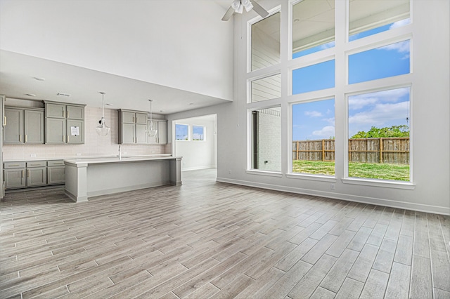 unfurnished living room featuring light wood-type flooring, sink, a high ceiling, and ceiling fan